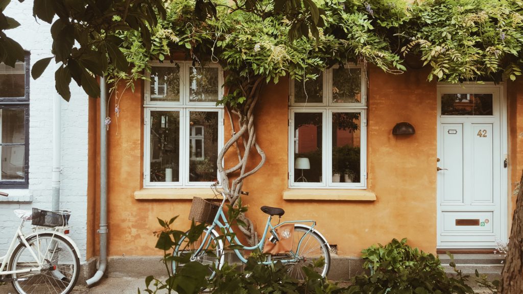 A bicycle leaning against the orange wall of a house.